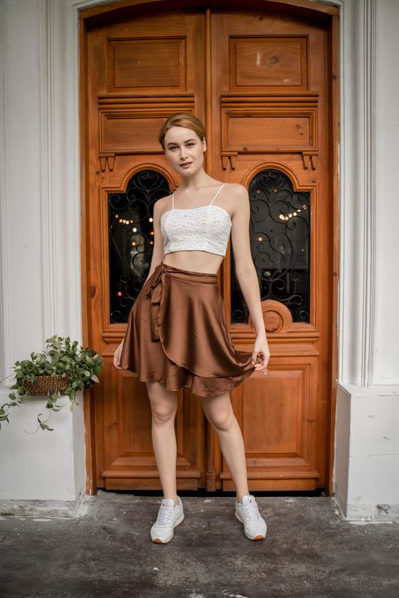 White lace crop top paired with a brown silk wrap skirt